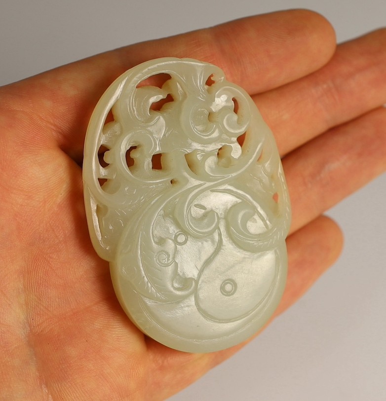 A Chinese white and russet skin jade oval plaque, 19th century, 6.4cm, wood stand